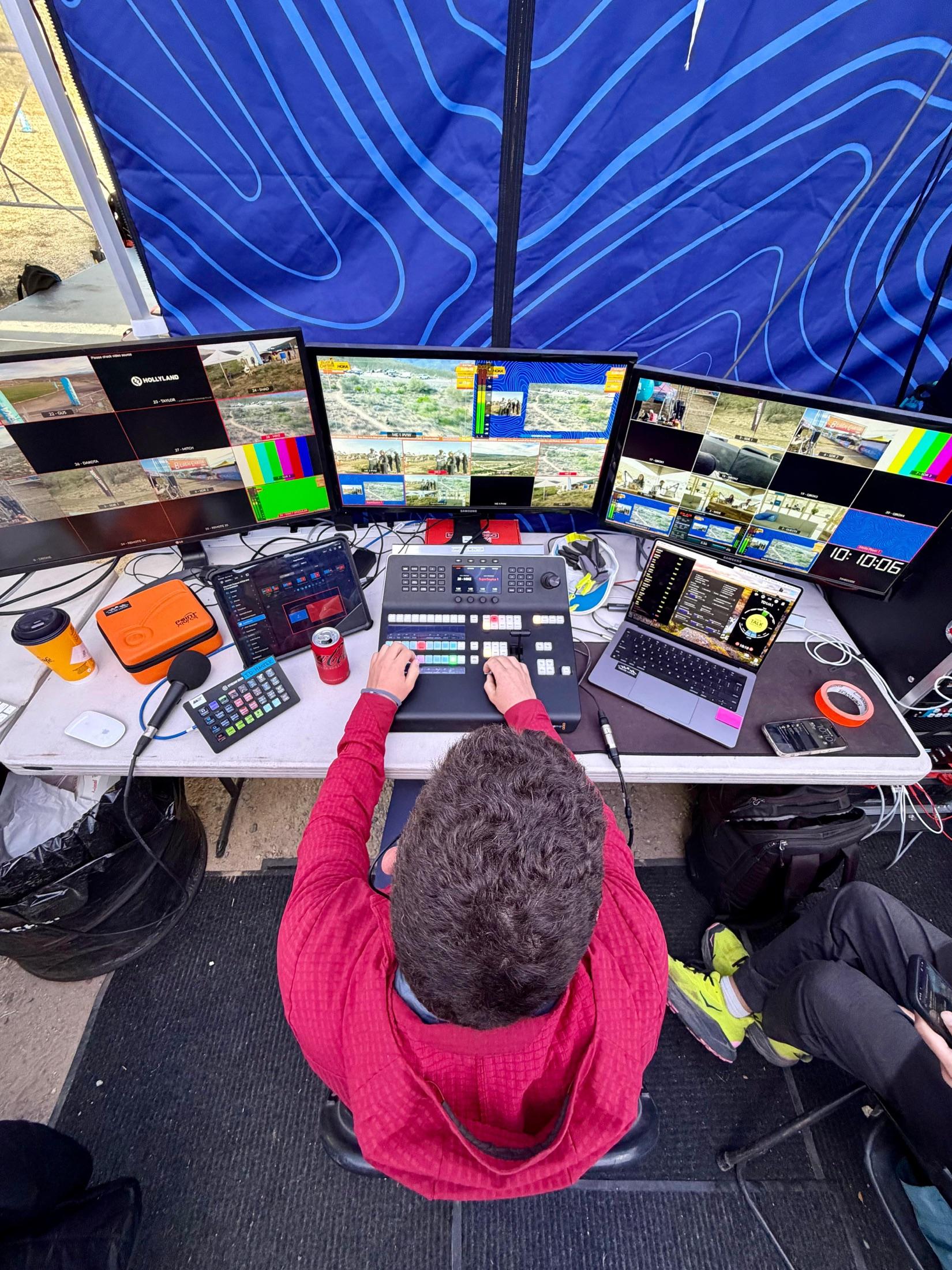 Trevor at a live production desk with multiview monitors, a switcher and a laptop